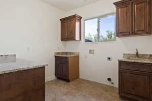 Washroom with hookup for a washing machine, electric dryer hookup, gas dryer hookup, and cabinet space