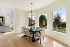 Dining room with light wood-style floors, a chandelier, baseboards, and a fireplace