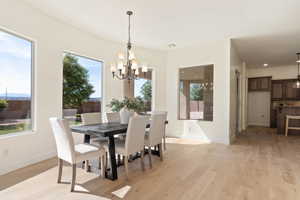 Dining area with a chandelier, light wood-style floors, and healthy amount of natural light