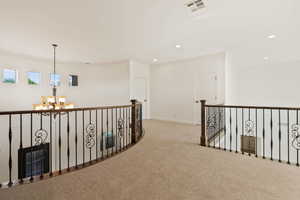 Hallway featuring a chandelier, carpet flooring, recessed lighting, baseboards, and an upstairs landing