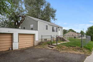 View of property exterior with a garage, fence, and driveway