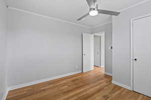 Unfurnished bedroom featuring crown molding, light wood-style flooring, baseboards, and a ceiling fan