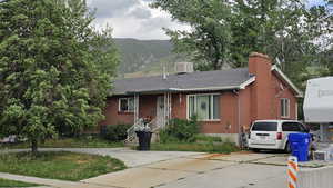 View of front of house with brick siding, a mountain view, a chimney and driveway.