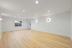 Basement family room featuring recessed lighting, modern wall sconces, and light LVP flooring