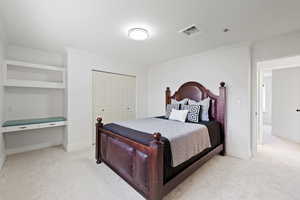 Carpeted bedroom featuring crown molding, a closet, and built-in desk