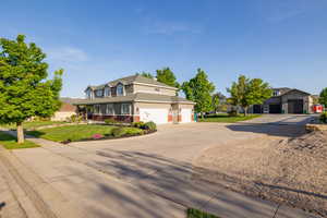 Traditional home with concrete driveway, a front yard, gravel RV parking, and multiple garages