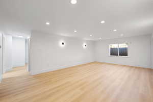 Basement family room featuring recessed lighting, modern wall sconces, and light LVP flooring