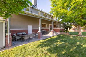 Rear view of property featuring a covered back patio and spacious backyard