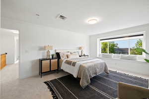 Primary bedroom flooded with natural light, featuring light carpet and custom roller shades