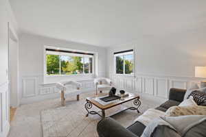 Front sitting room with large windows, wainscot walls, and light carpet
