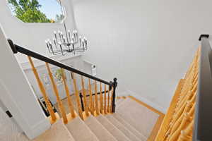Staircase featuring a modern traditional chandelier, custom wood railing, and patterned carpet runner