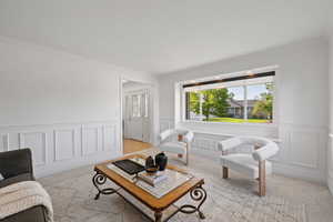 Front sitting room with large windows, wainscot walls, and light carpet