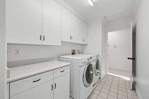 Laundry room featuring cabinet space, independent washer and dryer, and light tile floors