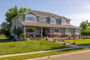 View of front of home featuring a covered porch, stucco and brick exterior, front yard and flower beds