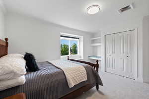 Carpeted bedroom featuring crown molding, a closet, and built-in desk