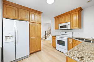 Second kitchen in basement mother-in-law apartment, featuring light wood cabinets, white appliances, granite countertops and LVP flooring.