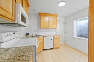 Second kitchen in basement mother-in-law apartment, featuring light wood cabinets, white appliances, granite countertops and LVP flooring.