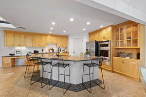Kitchen with stainless steel appliances, recessed lighting, a large island, quartz countertops and custom backsplash