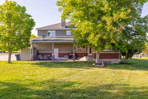 Rear view of property featuring a covered back patio and spacious backyard