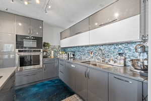 ADU kitchen with modern gray cabinets, quartz countertops, decorative backsplash and stainless steel appliances