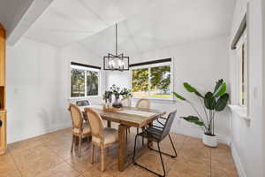 Dining space featuring a modern traditional chandelier, lofted ceilings, surrounded by windows with custom roller shades