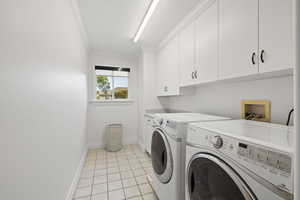 Laundry room featuring cabinet space, independent washer and dryer, and light tile floors