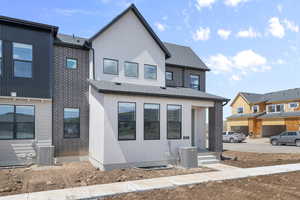 View of front of home with central AC unit and roof with shingles