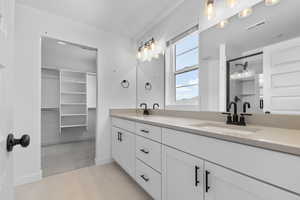 Full bath with double vanity, tile patterned floors, baseboards, and a shower with shower door