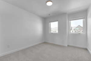 Unfurnished room featuring baseboards, light carpet, and a textured ceiling