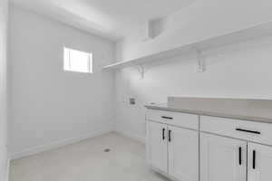 Washroom featuring hookup for a washing machine, baseboards, and cabinet space