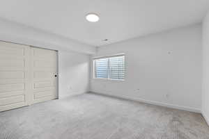 Unfurnished bedroom with light colored carpet, baseboards, and a closet