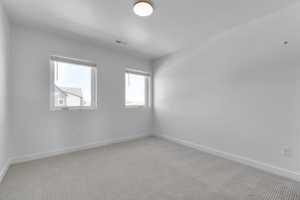 Spare room featuring light carpet and baseboards