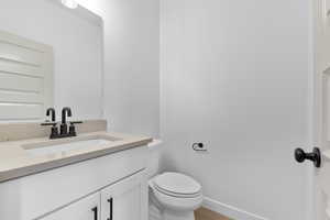 Bathroom featuring vanity, toilet, and baseboards