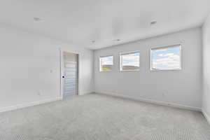 Spare room featuring light colored carpet and baseboards