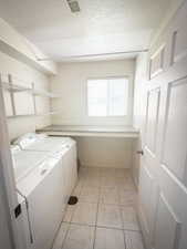 Laundry area featuring washer and dryer, a textured ceiling, and light tile patterned flooring