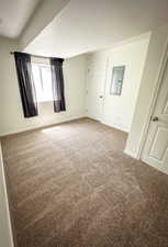 Carpeted spare room with a textured ceiling and baseboards