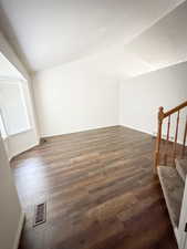 Additional living space with lofted ceiling, dark wood-type flooring, stairway, and baseboards