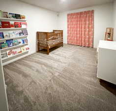 Bedroom with carpet floors, a crib, and baseboards