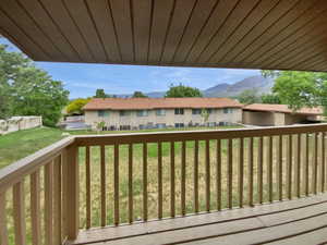 Wooden deck with a residential view, a mountain view, and a lawn