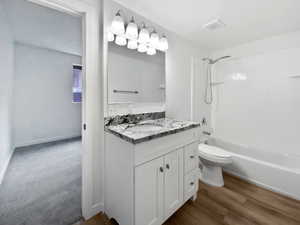 Full bath with  shower combination, vanity, toilet, and wood finished floors