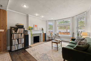 Living room featuring a fireplace, crown molding, plenty of natural light, and hardwood floors