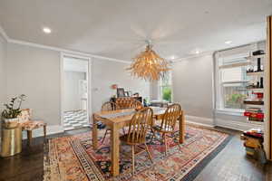 Open concept dining space with feature chandelier, hardwood floors, and two-tone paint