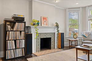 Living room featuring a fireplace, crown molding, plenty of natural light, and hardwood floors