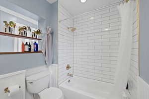 Full bathroom featuring a wainscoted wall, toilet, tiled shower / tub combo