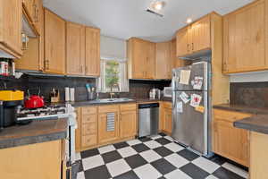Kitchen with stainless steel appliances, light wood cabinets, and tile floors
