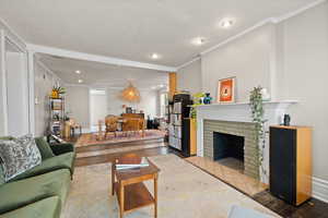 Living room featuring a fireplace, crown molding, plenty of natural light, and hardwood floors