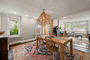 Open concept dining space with feature chandelier, hardwood floors, and two-tone paint