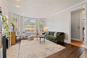 Living room featuring a fireplace, crown molding, plenty of natural light, and hardwood floors