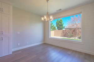 Unfurnished dining area featuring a chandelier, baseboards, and wood finished floors