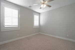 Spare room featuring ceiling fan, baseboards, and carpet